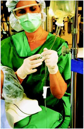 A nurse anesthetist injecting medication into the intravenous tube of a patient during surgery. (Photo Researchers Inc. Reproduced by permission.)