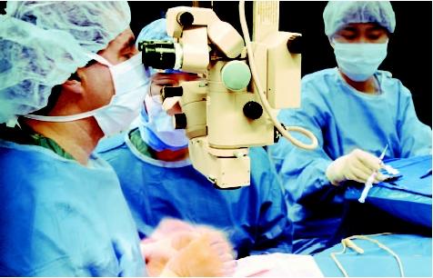 Surgeon performing microsurgery using specialized instruments and a microscope. (Custom Medical Stock Photo. Reproduced by permission.)